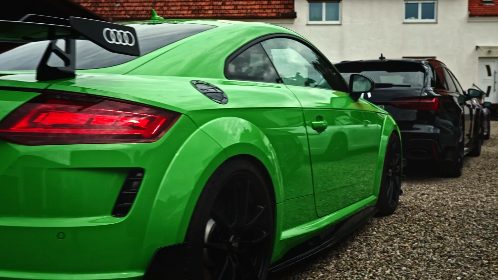 Heck eines grünen Audi TT mit Heckflügel und leuchtendem Rücklicht