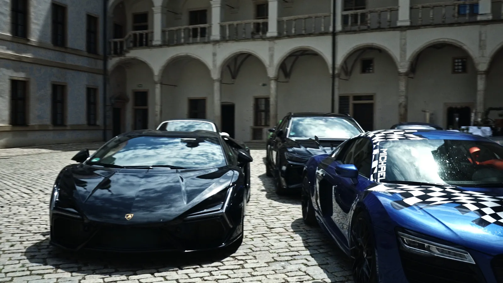 Schwarzer Lamborghini und blauer Audi R8 nebeneinander im Arkadenhof