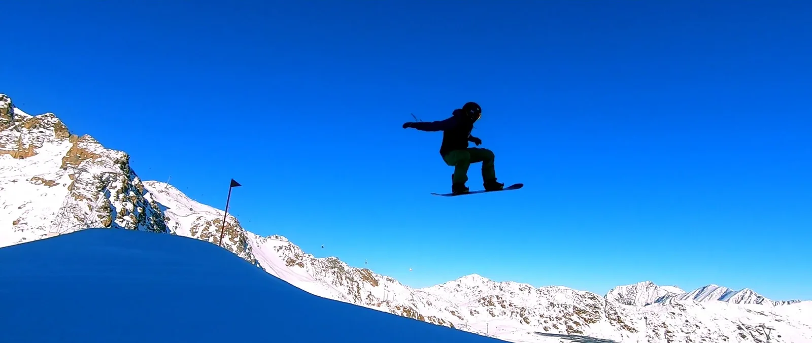 Silhouette eines Snowboarders im Sprung vor tiefblauem Himmel