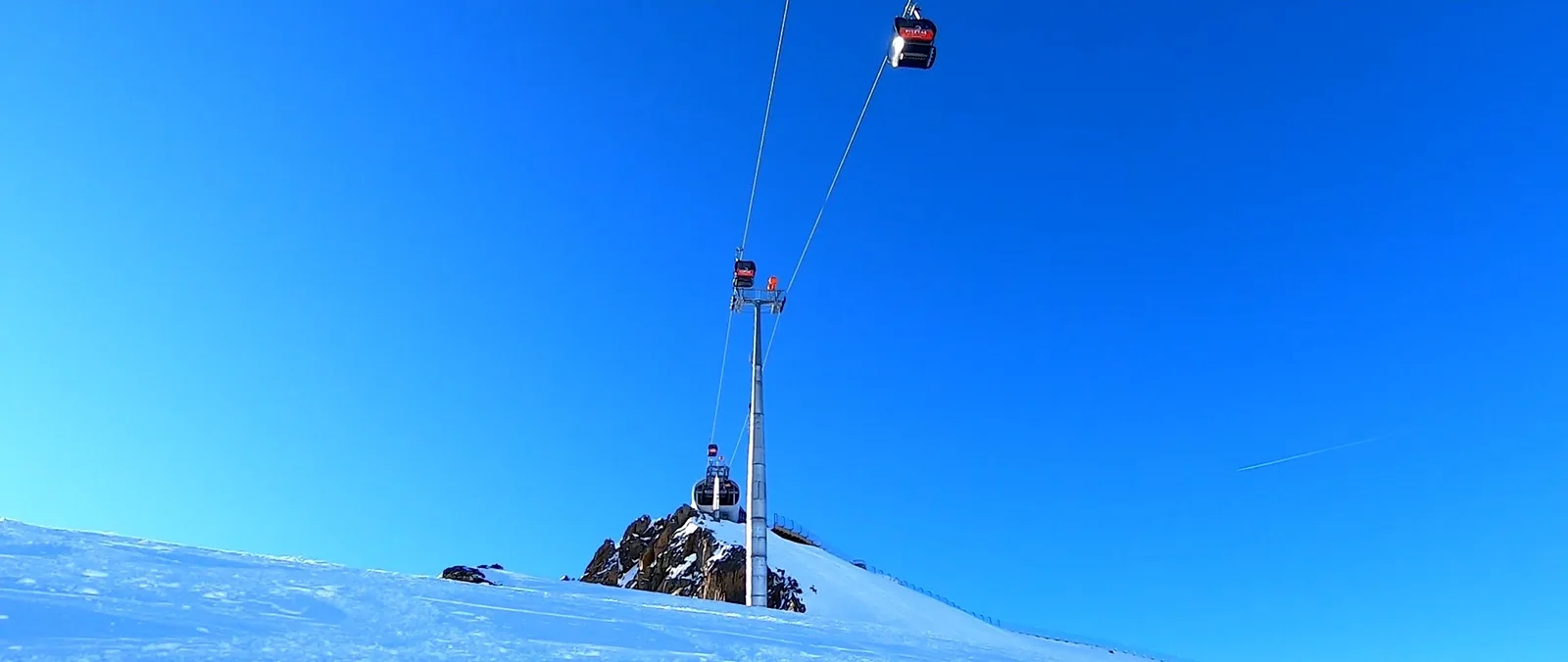 Gondeln einer Seilbahn vor wolkenlosem blauem Himmel