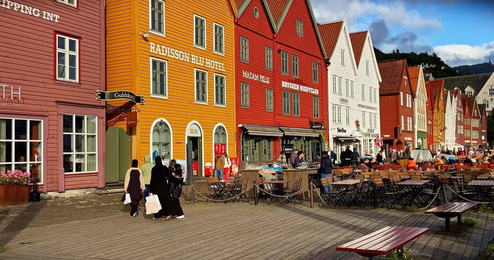 Bunte Holzhäuser und Straßencafés an einer Hafenpromenade