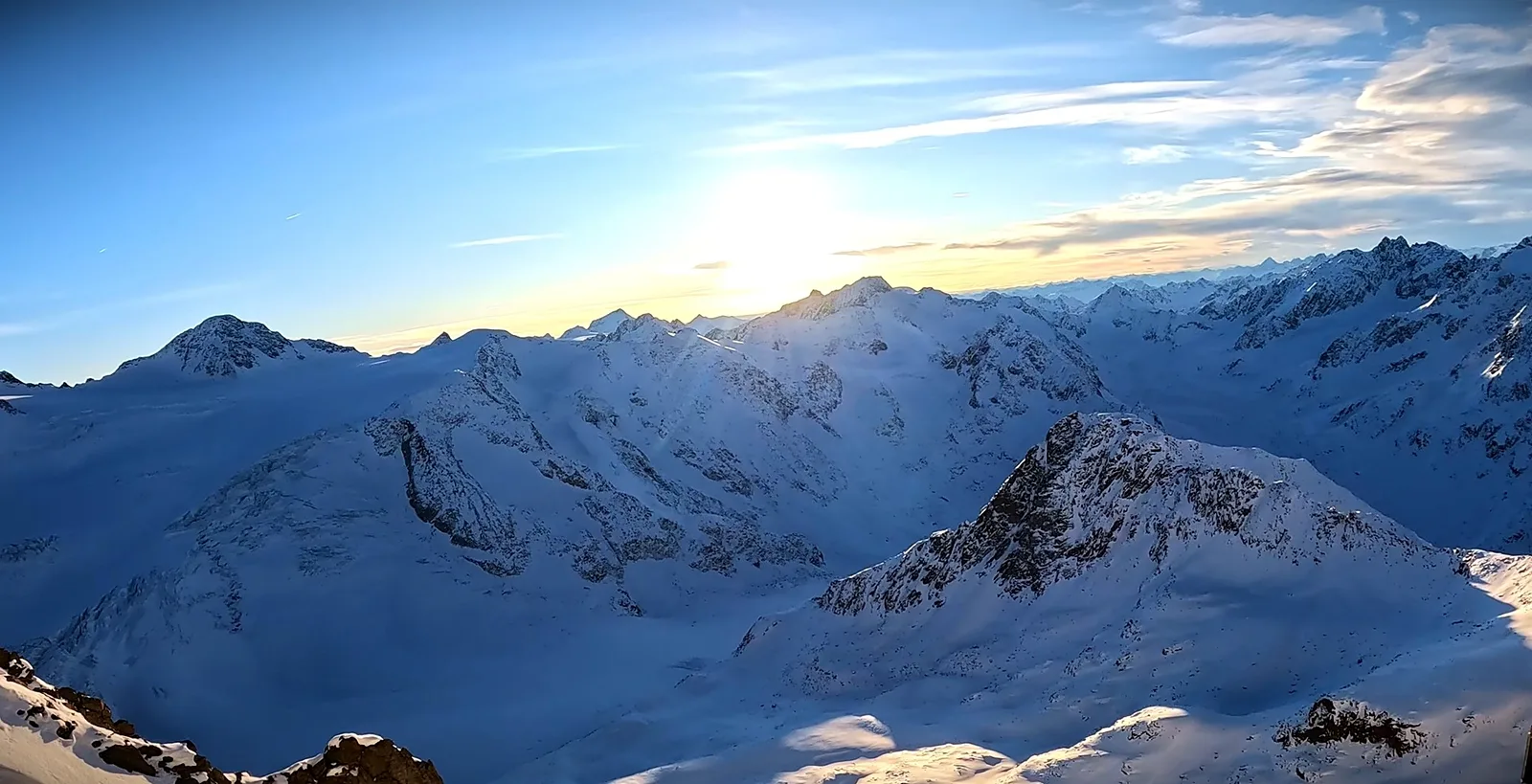 Sonne über einem weiten Panorama verschneiter Gipfel