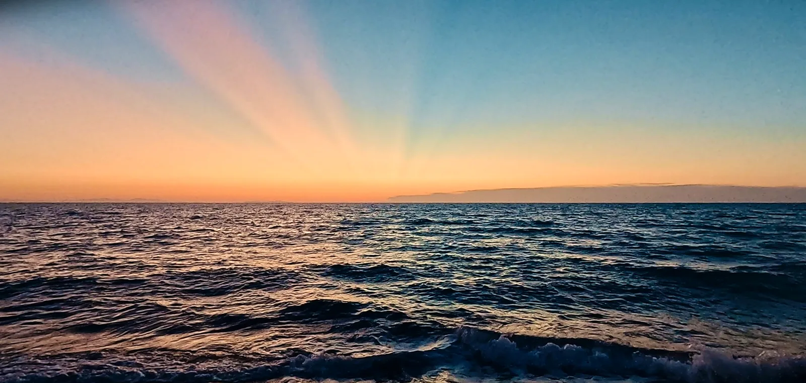 Lichtstrahlen fächern sich nach Sonnenuntergang über dem Meer auf