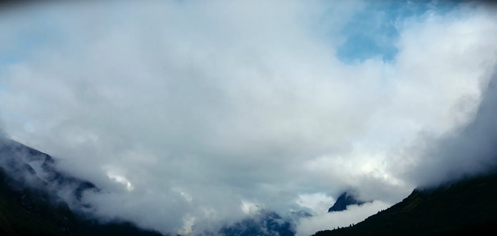 Dichte Wolken füllen ein Tal, nur eine Felsspitze ragt heraus